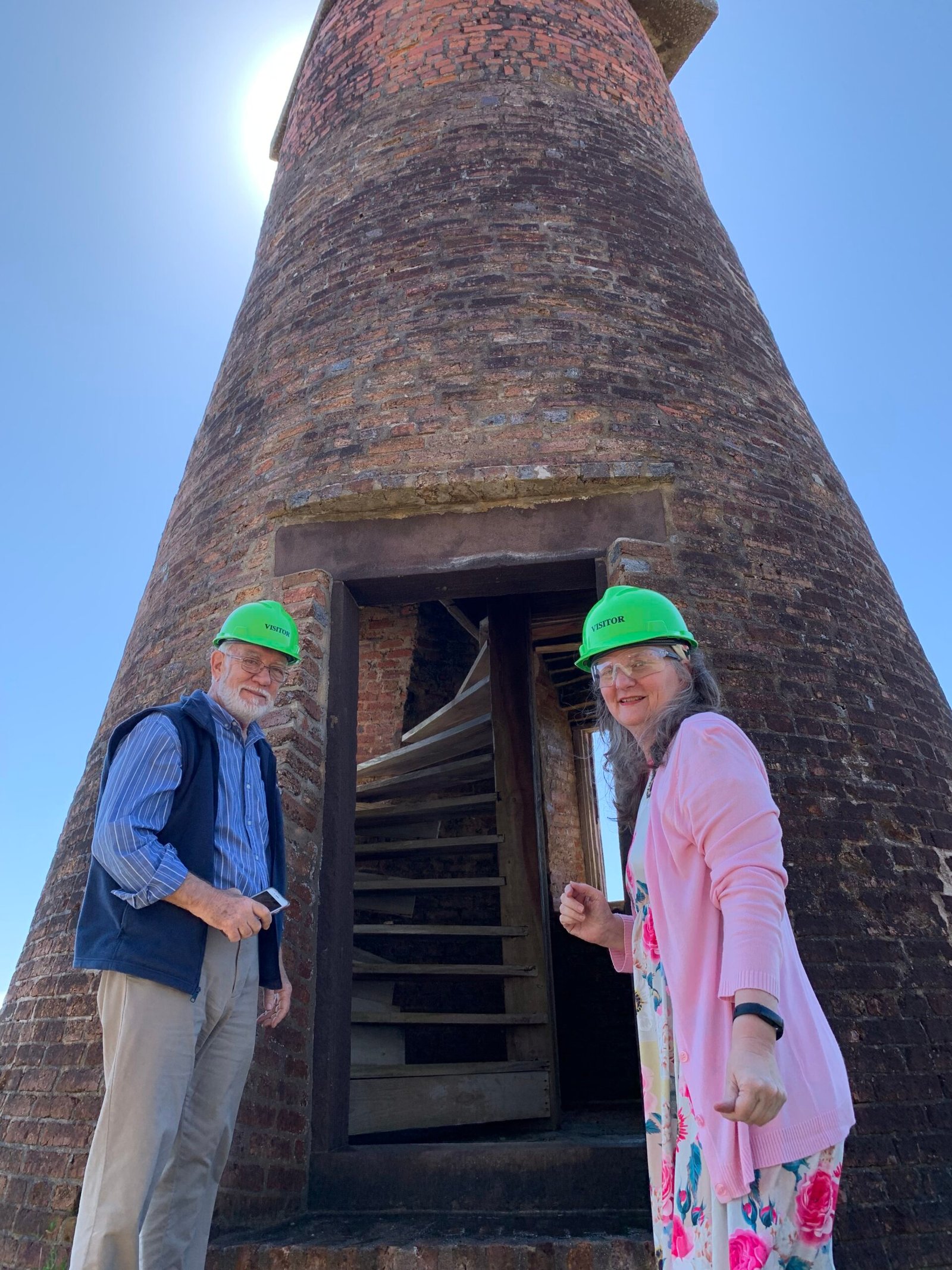 Two visitors in hard hats at a historic brick structure